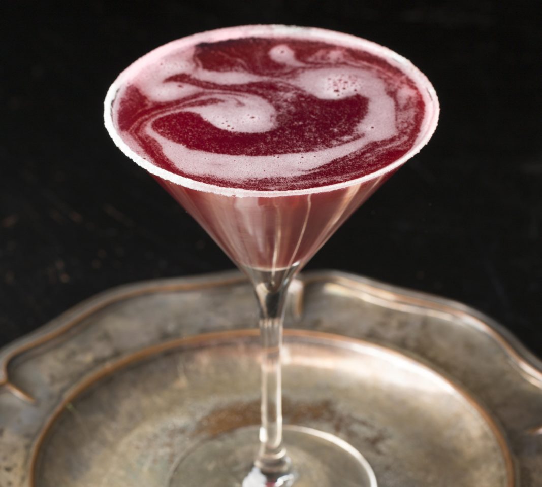 lemon pom cocktail in a martini glass on silver tray